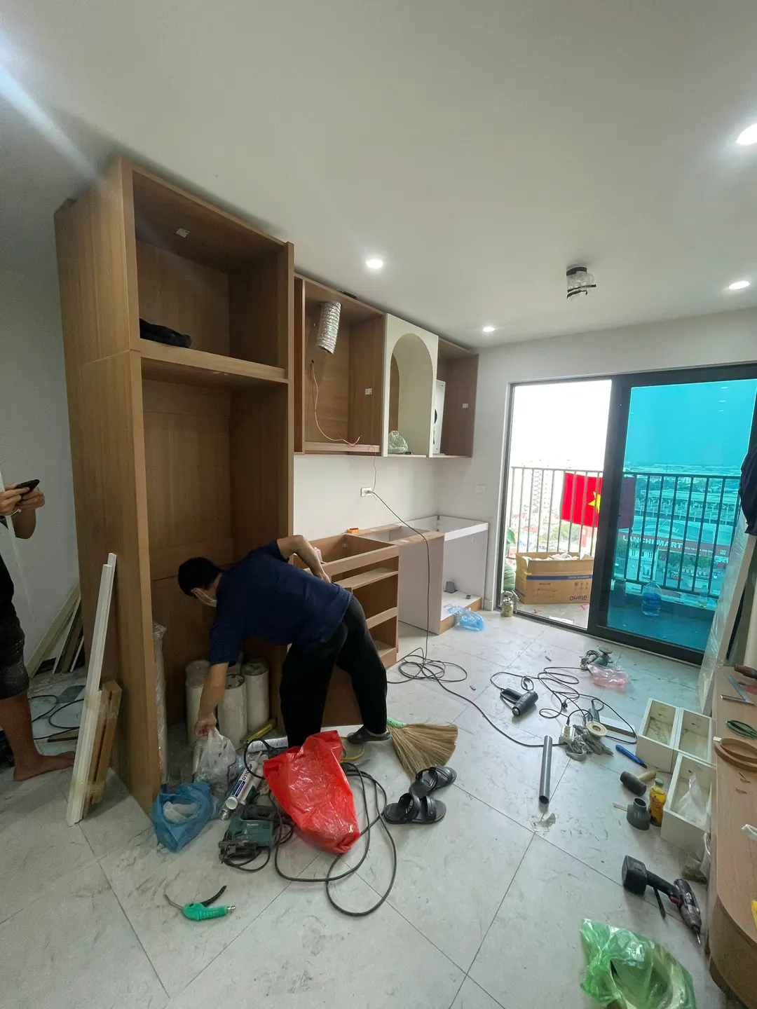 Thợ lắp tủ cao cạnh bếp trong căn hộ, dụng cụ và dây điện trên sàn